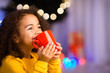 © Prostock-studio - Cute little african girl with cup of hot cocoa near Christmas tree