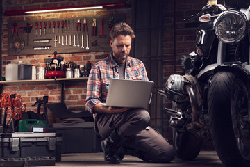 Mechanic checking data on a laptop in a workshop