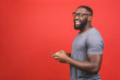 © denis_vermenko - Portrait of handsome excited cheerful joyful delightful african american guy wearing casual sending and getting messages to his lover isolated against red background. Using phone.