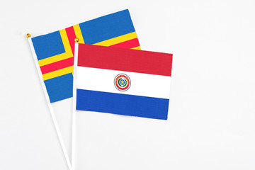 Paraguay and Aland Islands stick flags on white background. High quality fabric, miniature national flag. Peaceful global concept.White floor for copy space.