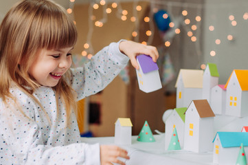 Little girl opening paper house from Christmas handmade advent calendar