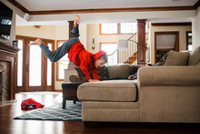 Young Boy Doing Handstand On Couch In Living Room During Winter