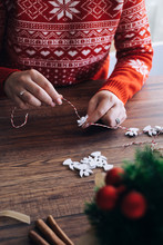 Woman Making Christmas Garland Of A White Wooden Angels