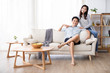 © Blue Jean Images - Happy young Chinese couple using smartphone in living room