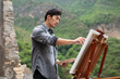 © Blue Jean Images - Young Chinese artist painting outdoors