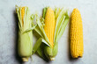 © Ramon Lopez/ADDICTIVE STOCK - Top view of steps of fresh ripe corn peeling on grey table