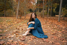 Melancholic Woman Sitting In Orange Autumn Park