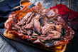 Traditional barbecue wagyu pulled beef in peach paper with Carolina BBQ sauce as closeup on a rustic board