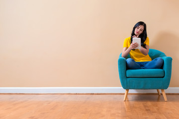 Wall Mural - Young woman using her tablet sitting in a chair