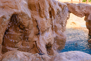 Small waterfall with turquoise water in the hotel pool