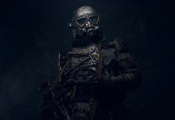 Cool cosplay costume of post - apocalypse knight, man is posing at dark photo studio.