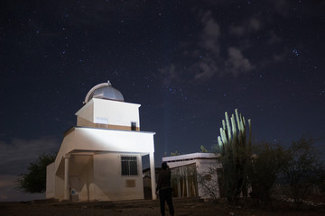 a lonely man lighting up the astronomical observatory and a spined cactus in starry night at tatacoa