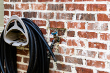 Garden Hose Hanging On Brick Wall Of House