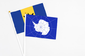 Antarctica and Barbados stick flags on white background. High quality fabric, miniature national flag. Peaceful global concept.White floor for copy space.