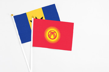 Kyrgyzstan and Barbados stick flags on white background. High quality fabric, miniature national flag. Peaceful global concept.White floor for copy space.