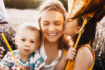 Wall Mural - portrait of a lovely young mother laughing with eyes closed while her daughter is kissing her on the