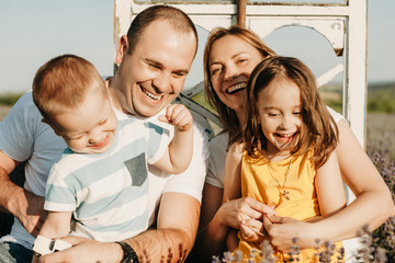 Wall Mural - portrait of a beautiful family laughing outdoor. father and mother embracing their kids laughing out