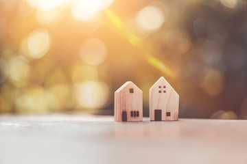 Wall Mural - Small model houses on wooden table with nature green bokeh sunlight abstract background.