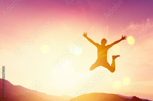 Happy man jumping at top of mountain with sunset sky abstract background Poster Mural XXL