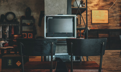 Blank space of monitor screen on vintage cafe background and retro black metal chair, use to put movie on blank screen