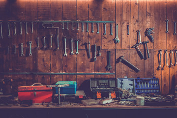 Workshop scene. Old tools hanging on wall in workshop, Tool shelf against a table and wall, vintage garage style