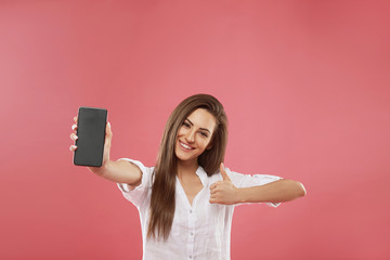 happy young beautiful woman posing isolated over pink wall background using mobile phone showing dis