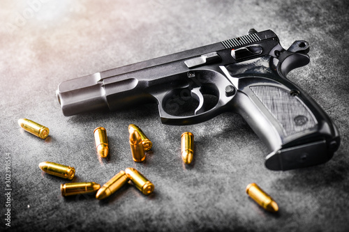 Photographie Hand gun with ammunition on dark stone background