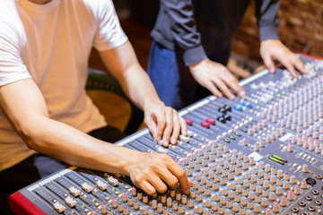 Wall Mural - sound engineer and producer mixing sound on audio mixing console in recording, broadcasting studio