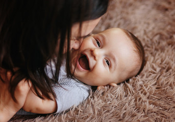 happy cheerful family. mother and baby kissing, laughing and hugging. home happiness