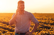 © Zoran Zeremski - Young farmer in filed examining soybean corp and talking at phone.