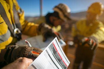 Wall Mural - Construction workers wearing a industry safety glove signing of high risk working at height permit on the opening field prior starting early day shift