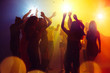 Holidays. A crowd of people in silhouette raises their hands on dancefloor on neon light background. Night life, club, music, dance, motion, youth. Yellow-blue colors and moving girls and boys.