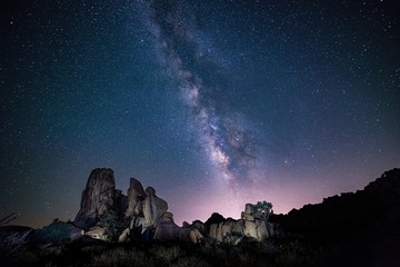Wall Mural - Beautiful shot of silhouettes of rocks under the purple sky full of stars - perfect wallpaper