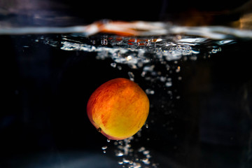 drop red apple in tank. water is splash on black background