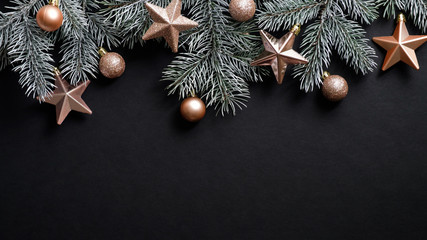 christmas banner. xmas tree branches decorated cooper stars and balls on black background. flat lay,