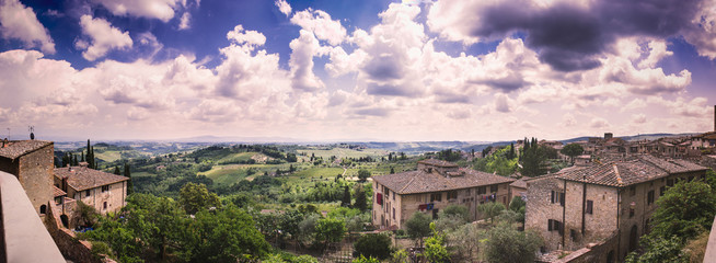 Wall Mural - Beautiful cumulus-clouded panorama from the top of the wall of the medieval tuscan town San Gimignano