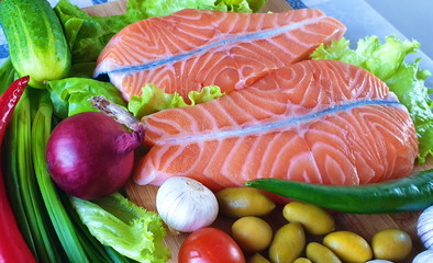 Fish Raw Salmon Two  steaks with vegetables and spices:  tomatoes,  lemon and olives cucumber green salat onion garlic lime  Healthy food diet concept Coral ,palette,Living Coral palette