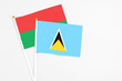 © sezerozger - Saint Lucia and Burkina Faso stick flags on white background. High quality fabric, miniature national flag. Peaceful global concept.White floor for copy space.