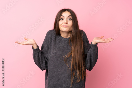Fotografía Young woman over isolated pink background having doubts while raising hands
