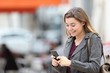 © Antonioguillem - Happy teen texting on cell phone walking in the street