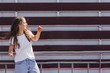 © Bohdan Melnyk - Young hipster woman leaning back on fence and making fun in front of urban wall