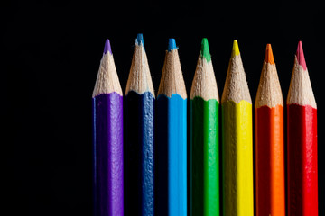 Coloured pencils isolated on black background close up. Vintage look Macro photography. Pencils Wallpaper. Bundle of rainbow colored pencils with selected focus on tips. Multicolored rainbow pencils.