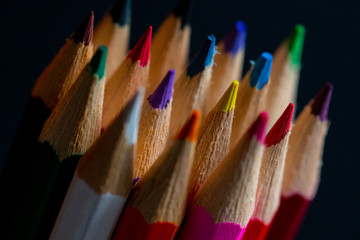 Coloured pencils isolated on black background close up. Vintage look Macro photography. Pencils Wallpaper. Bundle of rainbow colored pencils with selected focus on tips. Multicolored rainbow pencils.