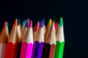 Coloured pencils isolated on black background close up. Vintage look Macro photography. Pencils Wallpaper. Bundle of rainbow colored pencils with selected focus on tips. Multicolored rainbow pencils.