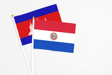 Paraguay and Cambodia stick flags on white background. High quality fabric, miniature national flag. Peaceful global concept.White floor for copy space.