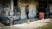 Woman Standing And Leaning Against Wall In Abandoned Gas Station