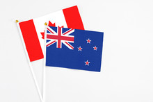 New Zealand And Canada Stick Flags On White Background. High Quality Fabric, Miniature National Flag. Peaceful Global Concept.White Floor For Copy Space.