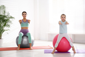 Wall Mural - Woman and daughter doing exercise with fitness balls at home