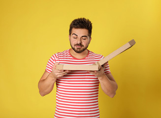 Wall Mural - Handsome man with tasty pizza on yellow background