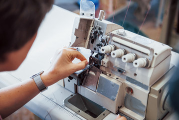 Wall Mural - Dressmaker woman sews clothes on sewing machine in factory